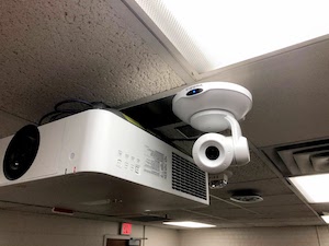 point/tilt/zoom camera mounted near a projector on the ceiling